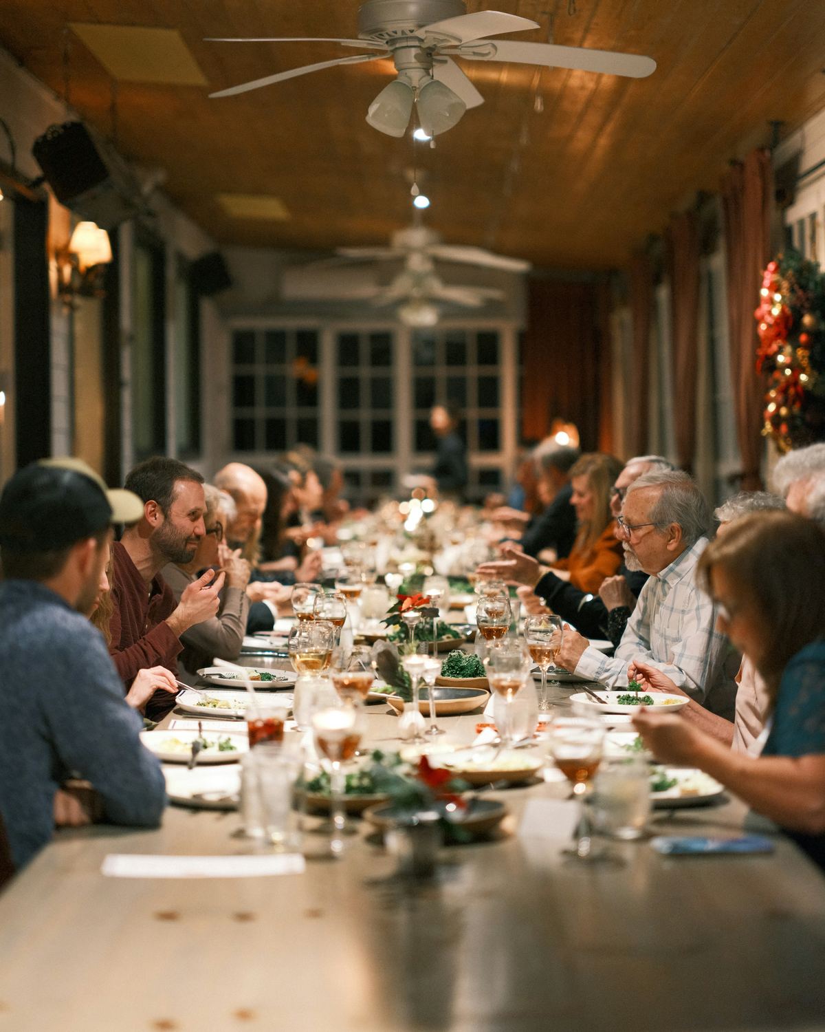 A long table of family and friends of several generations sharing a meal.