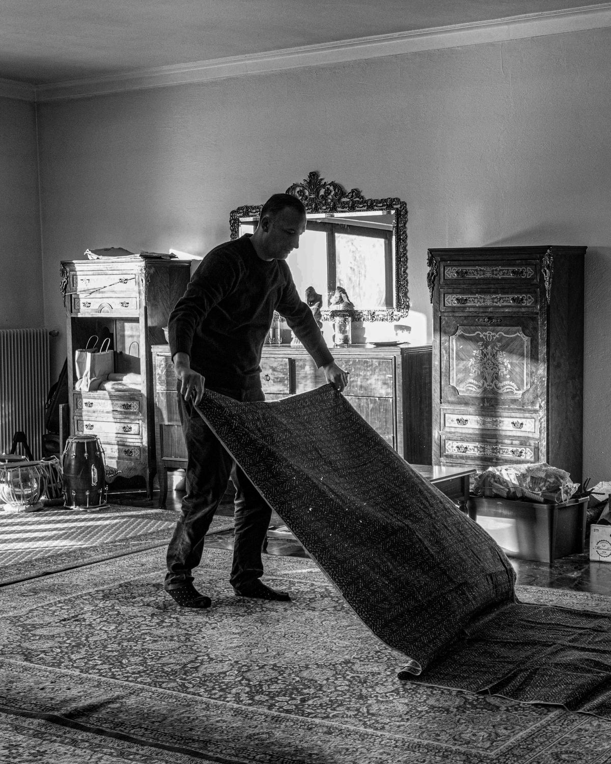 A mover laying a rug in an elegant living room during a move.
